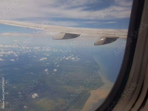 Looking through window aircraft during flight in wing with a nice blue clear sky and beautiful clouds. flying and traveling, view from airplane that can see outside.