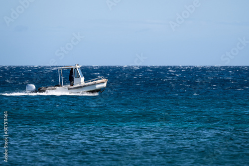 Small motor boat cruising on a calm pacific ocean on a sunny day, water, sky, and horizon, Maui, Hawaii
