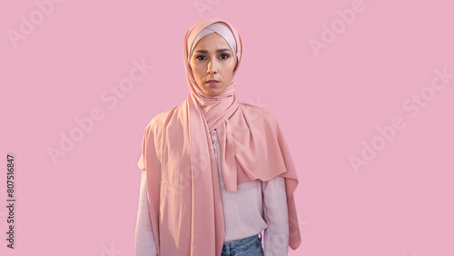 Scared woman. Fear anxiety. Female rights. Disturbed overwhelmed girl face in hijab muslim headscarf isolated on pink empty space background.