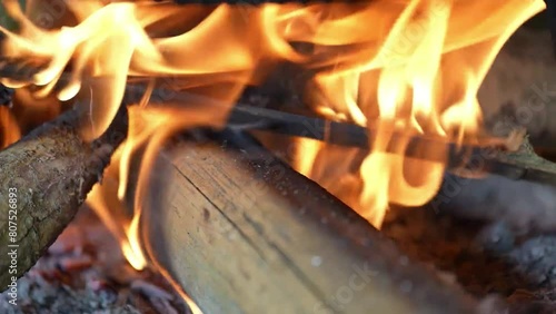 A roaring fire crackles merrily beneath a large frying pan, its flames licking the bottom and heating it to a fiery glow, in an outdoor cooking setting. photo