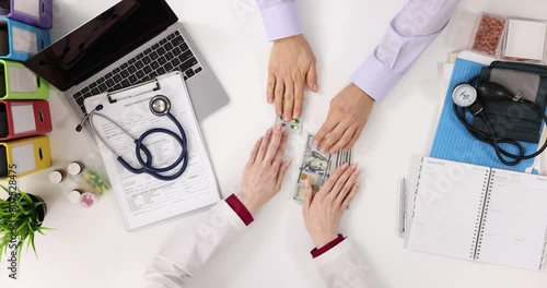 Hands of doctor and patient exchange money and pills, top view