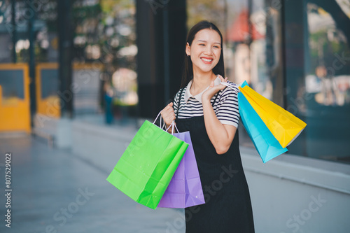 A woman is holding a bunch of shopping bags and smiling