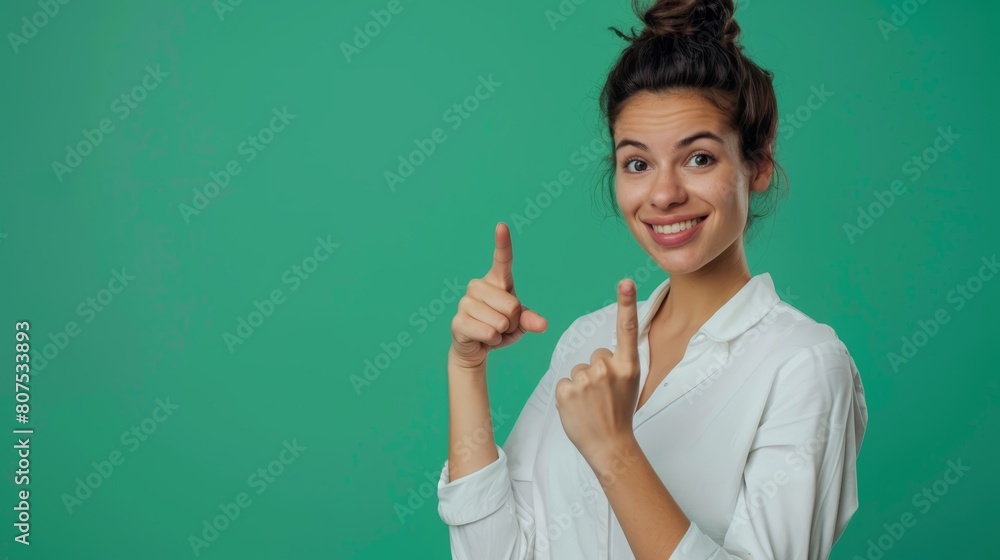 Young woman in green pointing upwards, excellent for educational and instructional content. Young woman in green pointing upwards, excellent for educational and instructional content.