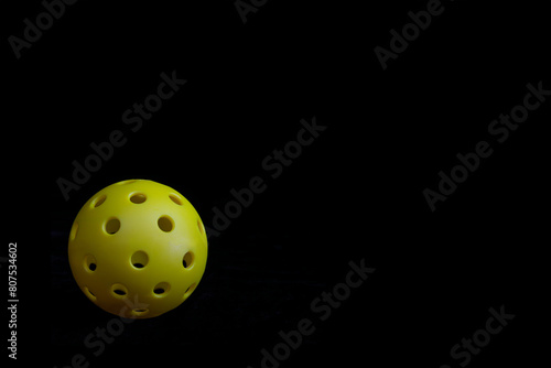 Yellow Pickleball isolated on a black background.