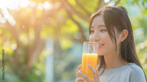 Young Asian woman drinking orange juice