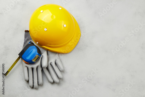 Happy labor day concept. Construction supplies, yellow helmet, tape measure on a grey background, copy space.