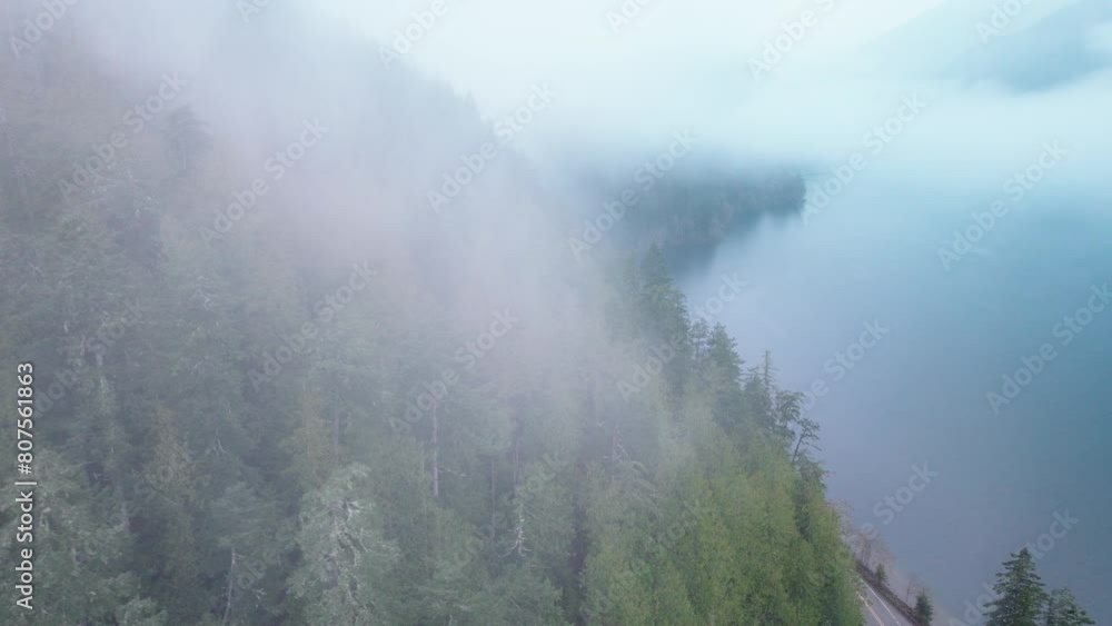 The early morning fog adds a mystical layer to this forest-lined highway that hugs the quiet lakeshore, enhancing the solitude and beauty of the scenic route. 4K footage. The early morning fog adds a mystical layer to this forest-lined highway that hugs the quiet lakeshore, enhancing the solitude and beauty of the scenic route. 4K footage.
