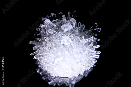 Sharp white diamond crystal highlighted from the bottom. Isolated on black