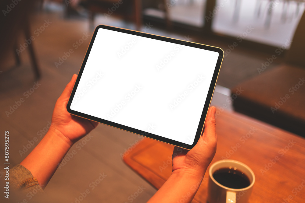 Mockup image of a woman holding digital tablet with blank white desktop screen in cafe Mockup image of a woman holding digital tablet with blank white desktop screen in cafe