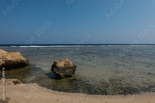 single coral rock in the water at the beach with deep blue sky