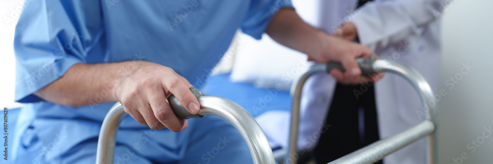 Physical therapist helps a male patient use a walker to practice walking. Support yourself from recovery from sore legs and ankles. Physical therapy service concept. Physical therapist helps a male patient use a walker to practice walking. Support yourself from recovery from sore legs and ankles. Physical therapy service concept.
