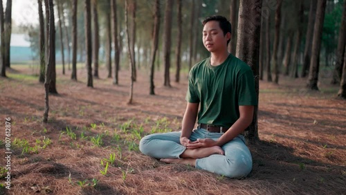 Man meditating in the park Sitting in the lotus position, practicing on a yoga mat, Zen, relaxing outdoors amidst nature in the morning, healthy lifestyle concepts. photo