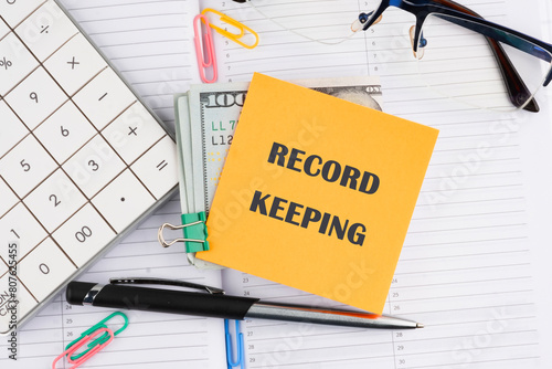 Record keeping text concept on a yellow sticker with money on a business notebook photo