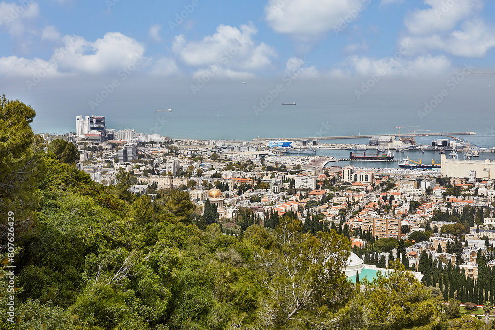 Seaport in the city of Haifa, panorama of the port and city buildings against the background of a blue sky with clouds