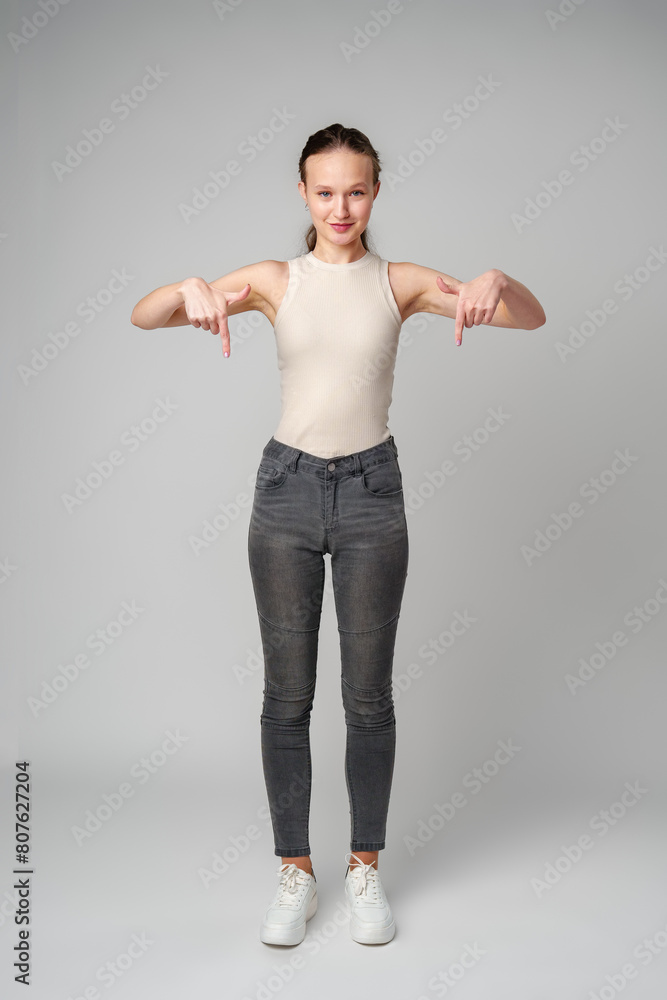 Young Woman in Tank Top Pointing Down in studio