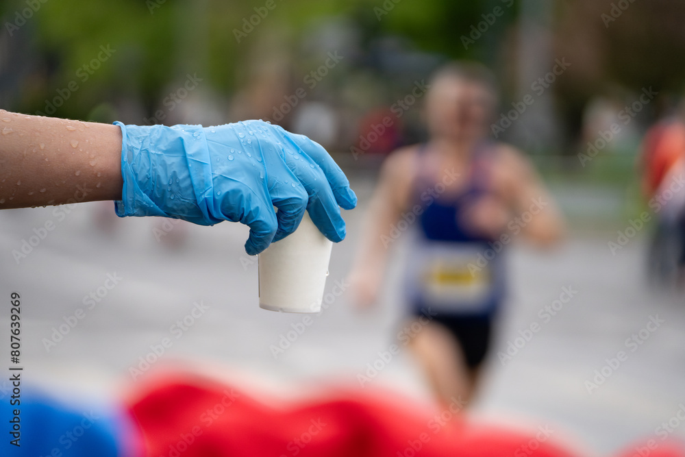 Runners of a marathon are provided with water at a hydration station. Running event, refreshment point along the route of long-distance run.