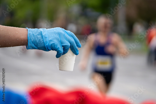 Runners of a marathon are provided with water at a hydration station. Running event, refreshment point along the route of long-distance run.