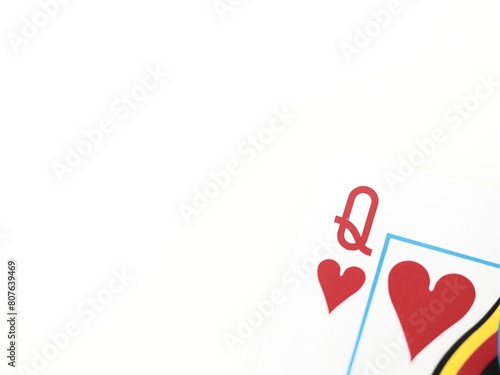 Close up of a Queen of hearts poker playing card in a corner on a white background with space for text