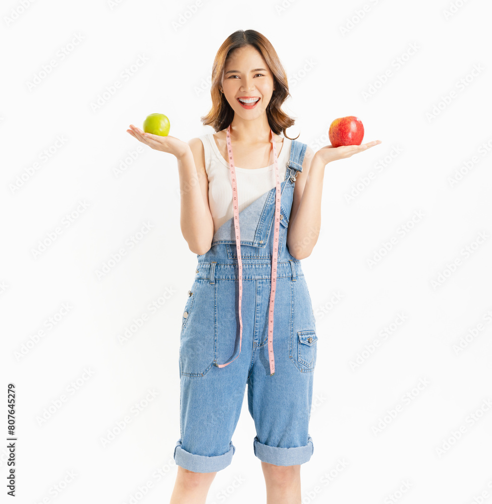 Charming joyful girl holding apple with measuring tape on white background, vitamins for healthy skin. Charming joyful girl holding apple with measuring tape on white background, vitamins for healthy skin.
