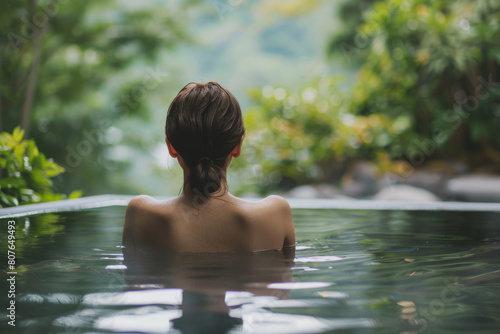 A woman is in onsen hot springs pool, enjoying the water. She is smiling and she is relaxed, wellness concept © Sunday Cat Studio