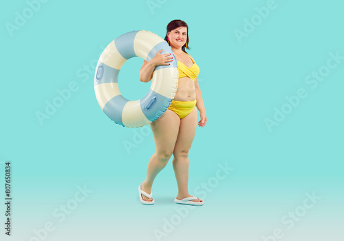 Fotografía Amazed obesity chubby woman in swimsuit posing with swimming circle on light blue background
