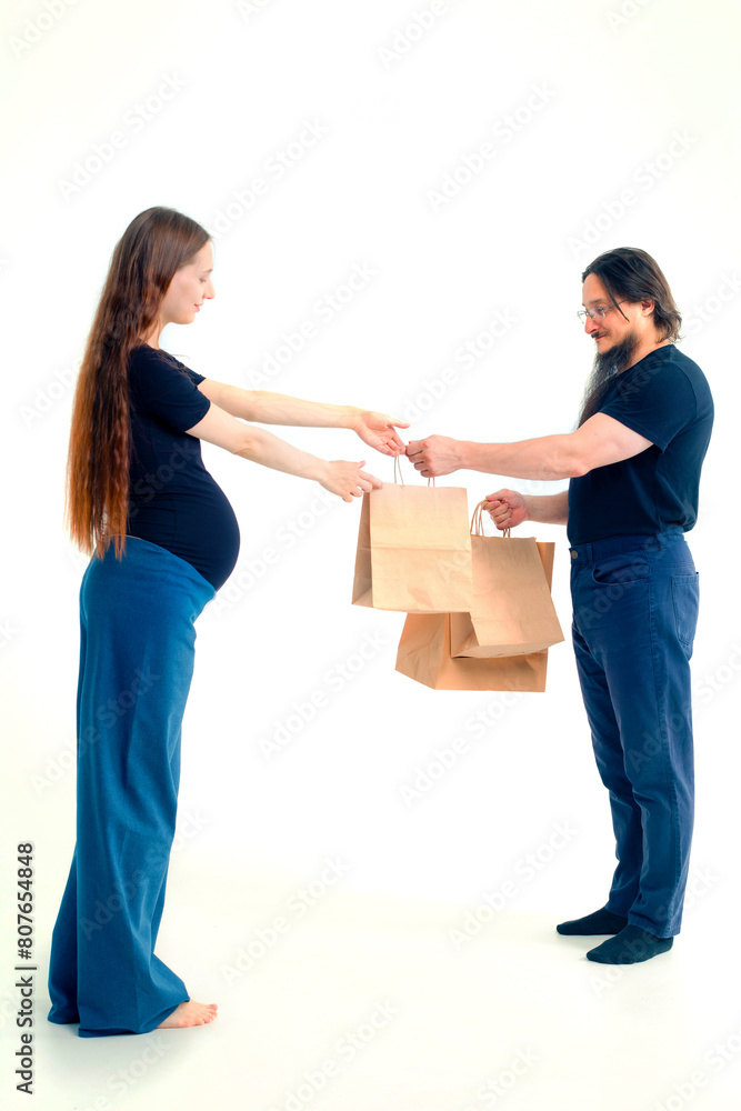 Portrait happy young pregnant woman and her husband with shopping bags and touching her big belly isolated on white background. Pregnancy shopping concept happy young family with shopping bags