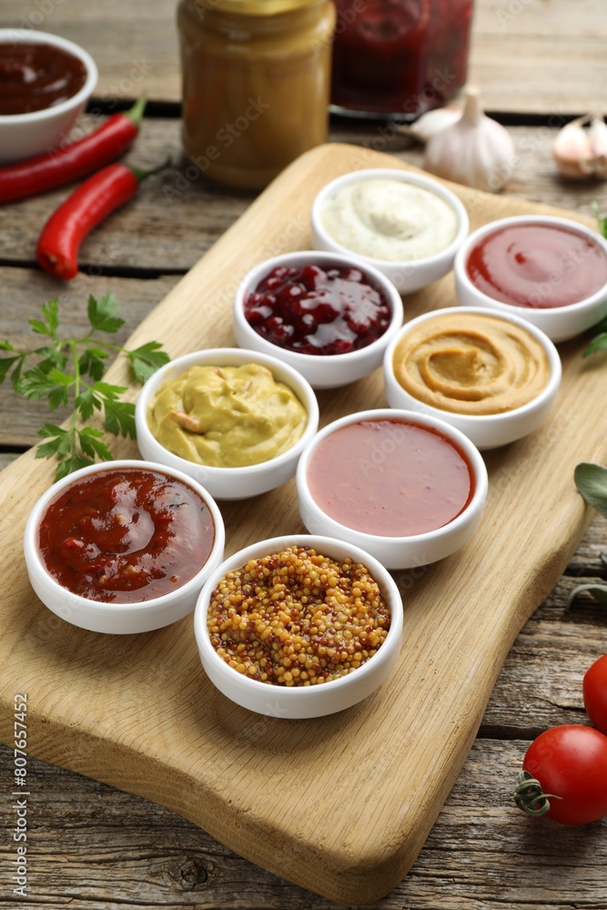 Different tasty sauces in bowls and ingredients on wooden table