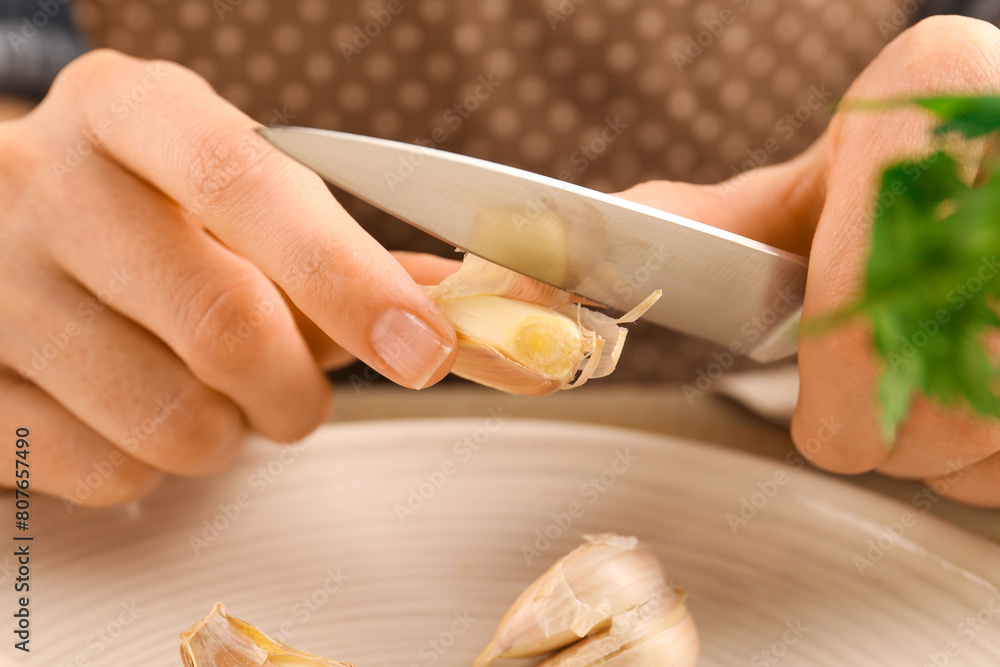 Woman peeling fresh garlic at table, closeup Woman peeling fresh garlic at table, closeup