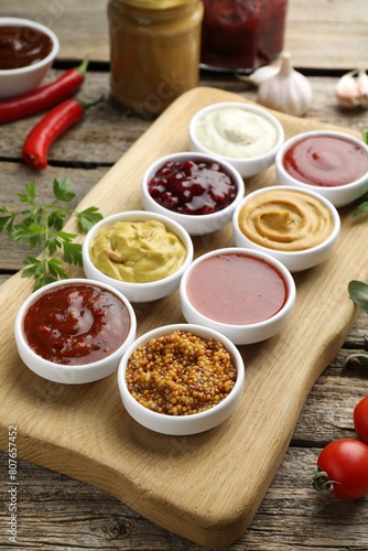 Photography Different tasty sauces in bowls and ingredients on wooden table