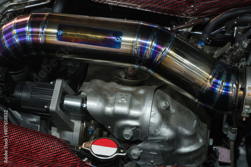 Close-up turbo engine and big iron pipe that installed on car bonnet for modify and tune up power speed of car