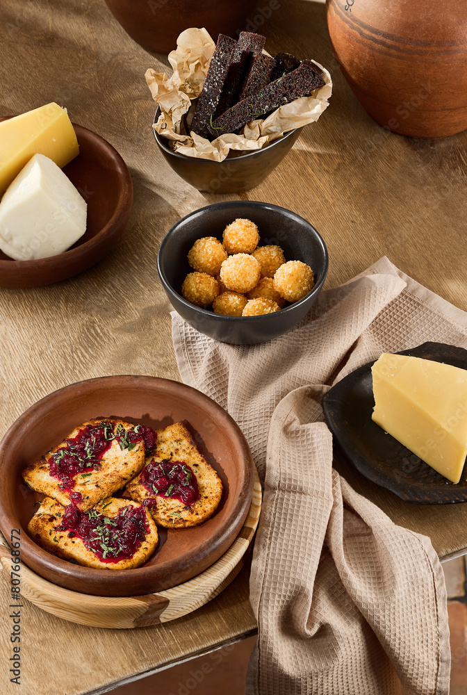 Traditional Russian Snack Set Featuring Garlic Toasts, Fried Cheese with Berries, and Cheese Balls Served on Rustic Wooden Table Traditional Russian Snack Set Featuring Garlic Toasts, Fried Cheese with Berries, and Cheese Balls Served on Rustic Wooden Table