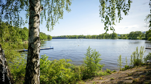 The valley of three ponds in Katowice. Beautiful green, recreational areas. Kayakers floating on the pond. Wooden pier.