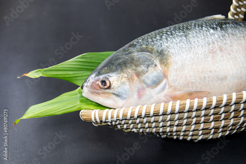 A Whole Hilsha fish in a boat-shaped handmade basket used as a gift hamper in festive occasions such as Jamai Shashthi, Pohela boishakh. photo