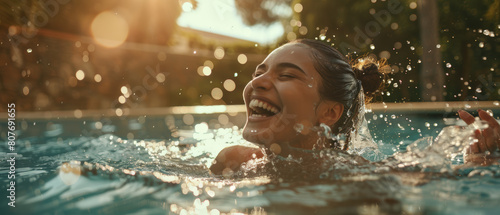 Exuberant woman enjoys a refreshing swim in a pool, surrounded by sunlit water droplets.