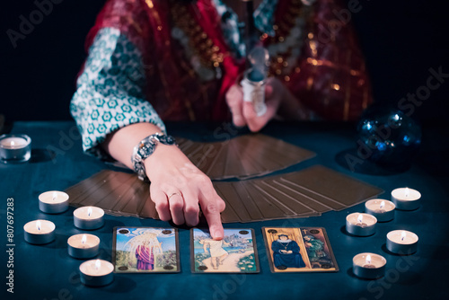 Tarot reader with tarot cards.Tarot cards face down on table near burning candles and crystal ball. © erika8213