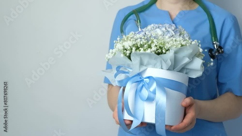 Bouquet of flowers in hands of doctor in blue medical uniform, space for text. Happy Doctor's Day photo