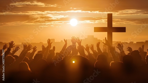 Christian worshipers raising hands up in the air in front of the cross photo