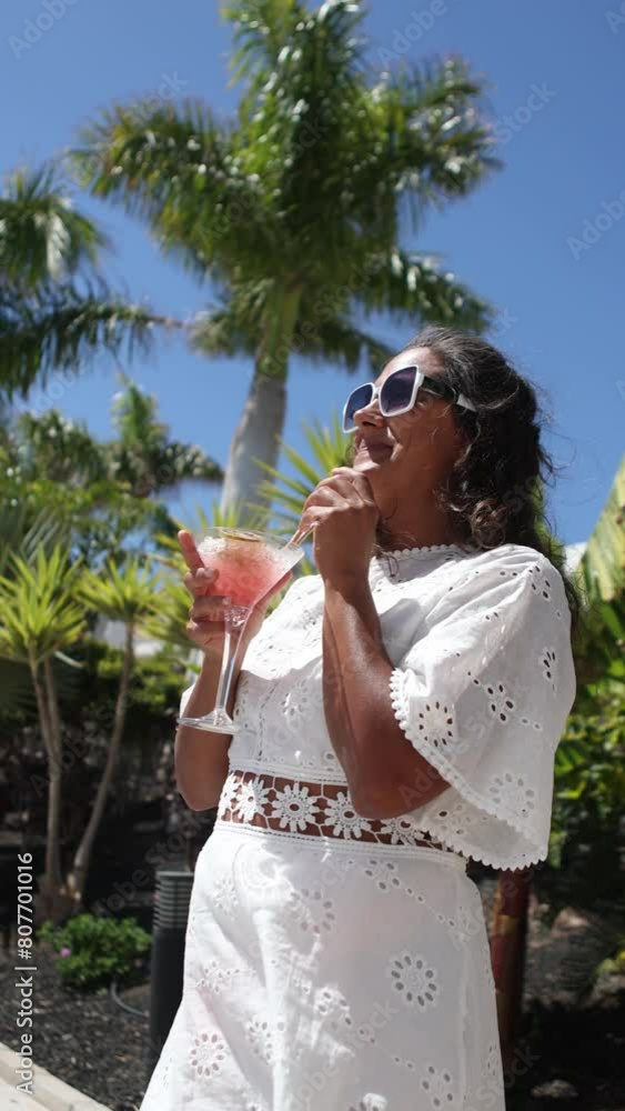 Elegant woman enjoying a cocktail under palm trees Elegant woman enjoying a cocktail under palm trees