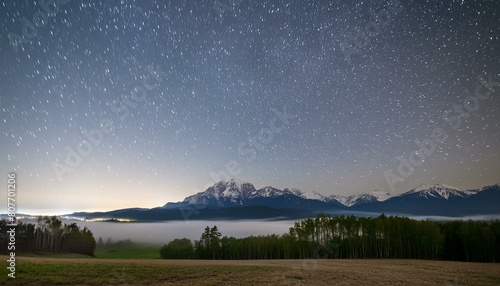 a night sky filled with stars and a mountain range in the distance