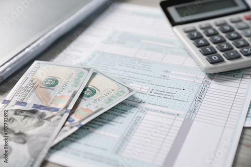 Payroll. Tax return forms, calculator and dollar banknotes on table, selective focus