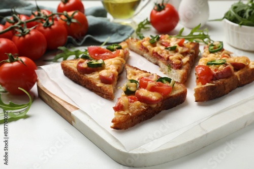 Tasty pizza toasts and ingredients on white marble table, closeup