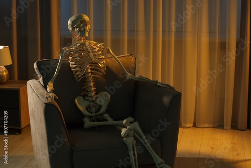 Waiting concept. Human skeleton sitting in armchair indoors