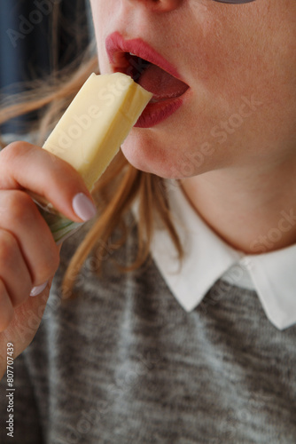 Close up of woman mouth eating a piece of holland cheese, healthy snack at lunchtime.
