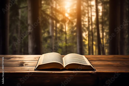 Open book on wooden table, forest background