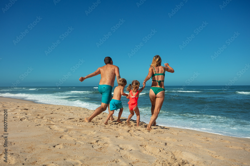 Family enjoys sunny beach day together walk along sandy seashore Family enjoys sunny beach day together walk along sandy seashore
