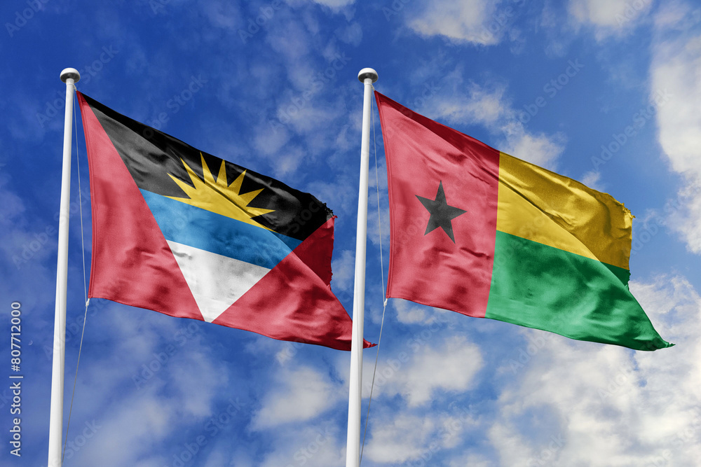 3d illustration. Antigua and Barbuda and Guinea-Bissau Flag waving in sky. High detailed waving flag. 3D render. Waving in sky. Flags fluttered in the cloudy sky. 3d illustration. Antigua and Barbuda and Guinea-Bissau Flag waving in sky. High detailed waving flag. 3D render. Waving in sky. Flags fluttered in the cloudy sky.