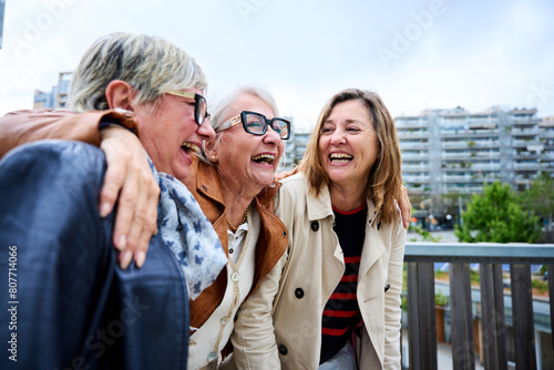 Obraz na plátně Group of three mature caucasian women enjoying embracing walk together laughing outdoor