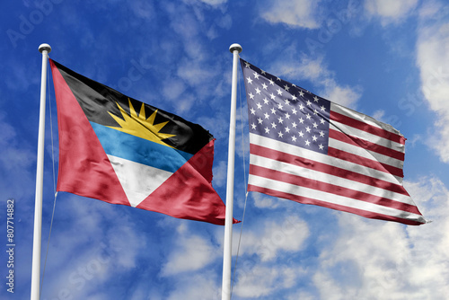 3d illustration. Antigua and Barbuda and  United States Flag waving in sky. High detailed waving flag. 3D render. Waving in sky. Flags fluttered in the cloudy sky.