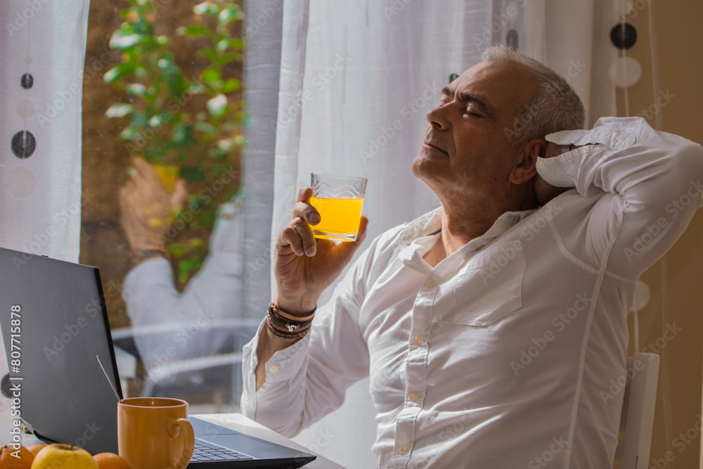 Fototapeta premium relaxed mature man having breakfast at his workplace