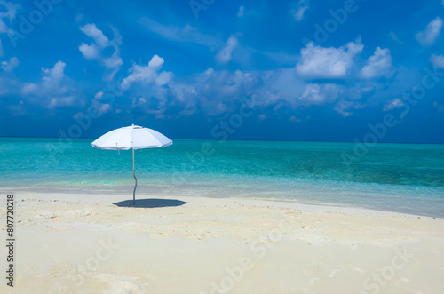 Summer tropical with white umbrella on the beach with  blue sky background